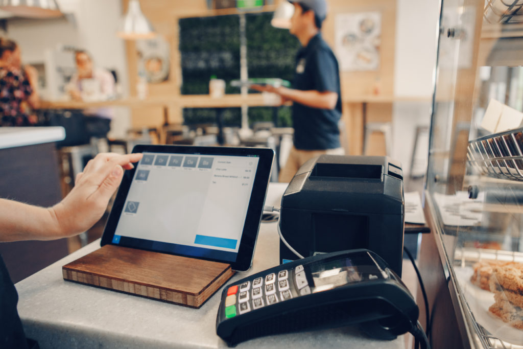 Closeup shot of cashier hands. Seller using touch pad for accepting client customer payment. Small business of coffee shop cafeteria.